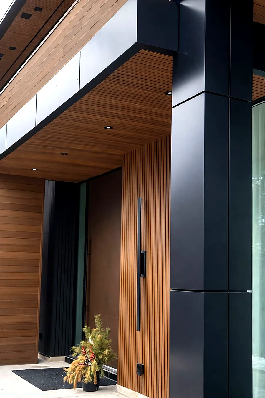Warm wood-look fluted panels framed by black ACM at a front entrance