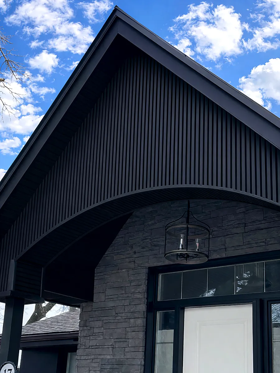 Grey stone veneer base under a black vertical metal gable